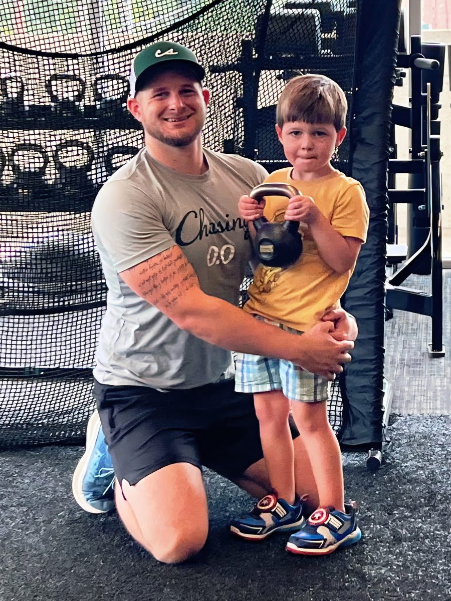 Brian kneeling with his son, who is holding a kettlebell